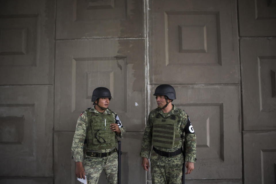 Military police wearing the insignia of the new National Guard provide perimeter security while a migration agent waits to check documents of passengers in passing transport, at an immigration checkpoint in El Manguito, south of Tapachula, Mexico, Friday, June 21, 2019. Mexico's foreign minister says that the country has completed its deployment of some 6,000 National Guard members to help control the flow of Central American migrants headed toward the U.S. (AP Photo/Oliver de Ros)