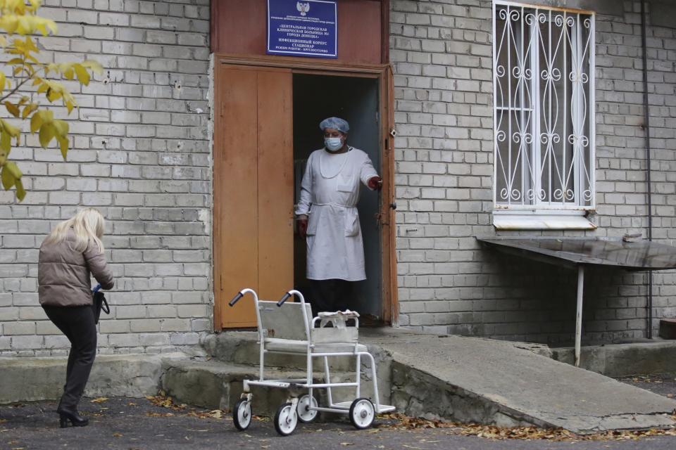 A medical worker stands at an enter of a hospital treating COVID-19 patients in Donetsk, controlled by Russia-backed separatists, Ukraine, Thursday, Oct. 14, 2021. The Russia-backed separatist authorities in eastern Ukraine are reporting the largest spike in new coronavirus infections since the start of the pandemic, saying the health care system has been overwhelmed. The health authorities in the Donetsk region of 2.2 million reported over 1000 new confirmed infections and about hundred coronavirus deaths in the past 24 hours. (AP Photo/Alexei Alexandrov)