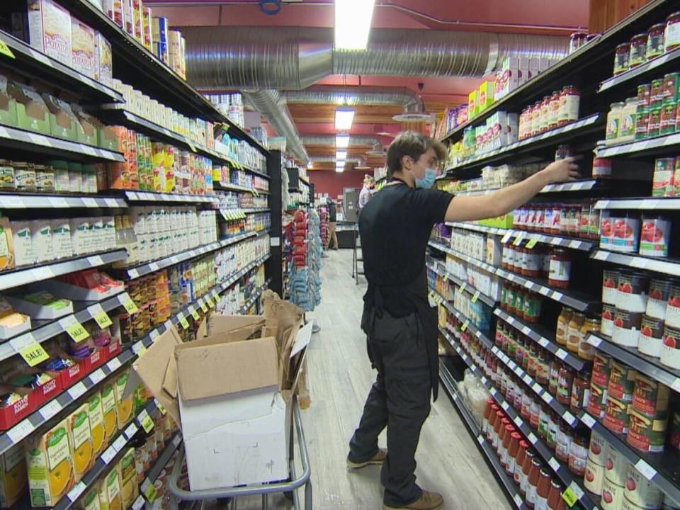 An employee at Blush Lane Organic Market on Whyte Avenue stocks shelves, as the store has adjusted the way it orders shipments, often days behind schedule.  (Sam Martin/CBC - image credit)