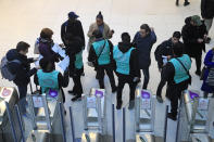 Metro information workers guid passengers next to a closed access at Gare du Nord train station in Paris, Wednesday, Dec. 18, 2019. With French President Emmanuel Macron under heavy pressure over his pension reform plans, government officials are meeting with employers and unions on Wednesday to consider the way forward. (AP Photo/Michel Euler)