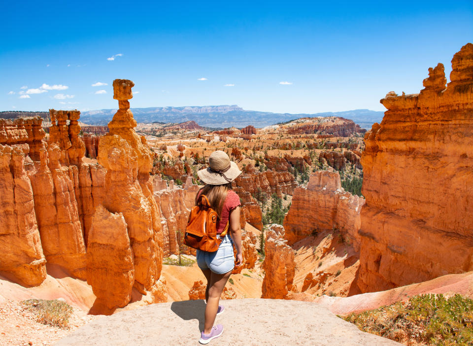 Woman standing next to Thor's Hammer hoodoo on top of  mountain looking at beautiful view. Bryce Canyon National Park, Utah, USA