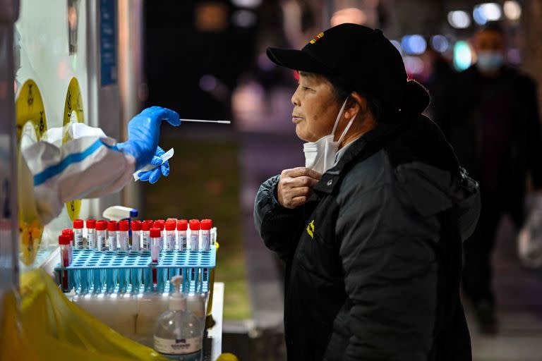 A health worker takes a swab sample from a woman to test for the Covid-19 coronavirus in the Huangpu district in Shanghai on December 19, 2022. (Photo by Hector RETAMAL / AFP)