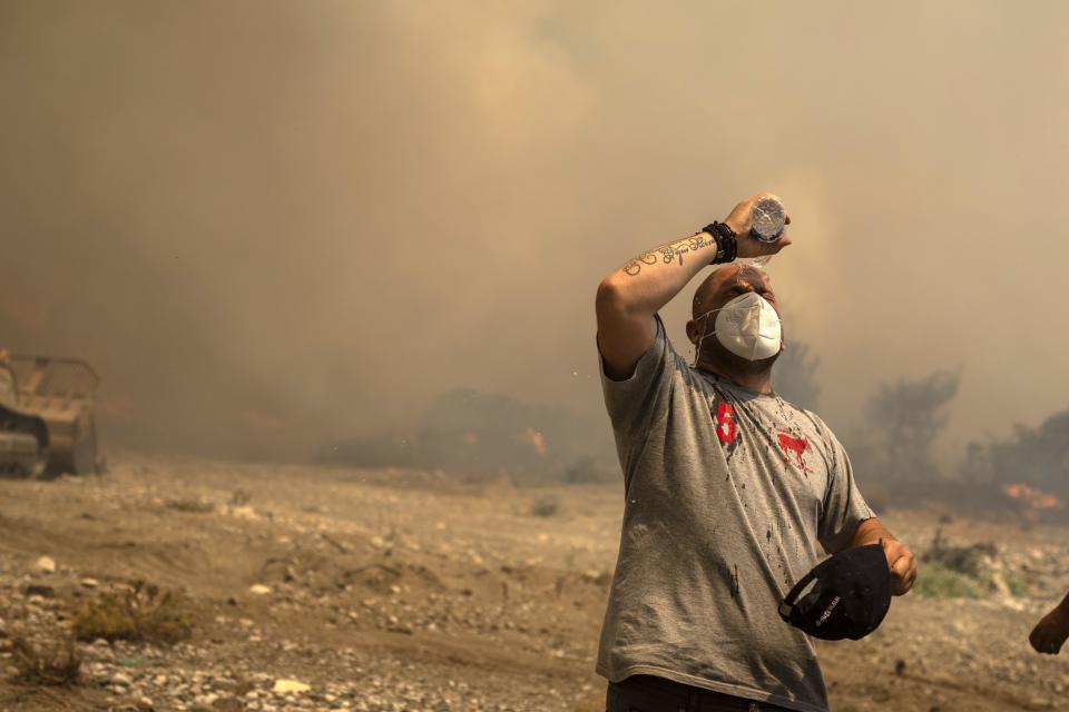 A volunteer cools himself during a wildfire in Vati village, on the Aegean Sea island of Rhodes, southeastern Greece, on Tuesday, July 25, 2023. A third successive heat wave in Greece pushed temperatures back above 40 degrees Celsius (104 degrees Fahrenheit) across parts of the country Tuesday following more nighttime evacuations from fires that have raged out of control for days. (AP Photo/Petros Giannakouris)