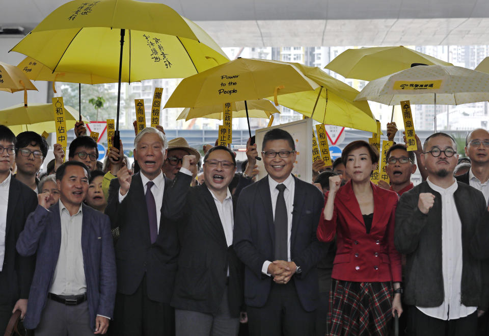 Occupy Central leaders, from right, Shiu Ka Chun, Tanya Chan, Chan Kin Man, Benny Tai, Chu Yiu Ming and Lee Wing Tat shout slogans before entering a court in Hong Kong, Monday, Nov. 19, 2018. Nine leaders of the 2014 Hong Kong pro-democracy movement stand trial today. The co-founders of the "Occupy Central" campaign - legal Professor Benny Tai Yiu-Ting, sociology professor Chan Kin-man and retired pastor Chu Yiu-ming - are facing charges related to the planning and implementation of the campaign which became part of the large-scale pro-democracy Umbrella Movement protests which were carried out 79 days between September and December 2014. (AP Photo/Vincent Yu)