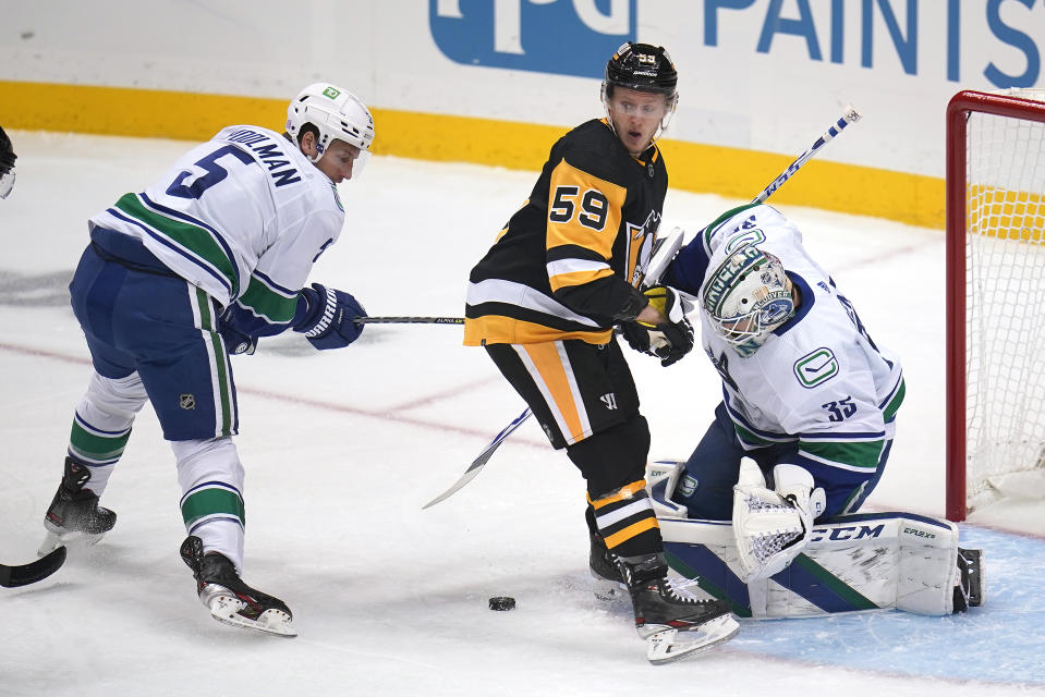 Pittsburgh Penguins' Jake Guentzel (59) can't find a rebound in front of Vancouver Canucks goaltender Thatcher Demko (35) with Tucker Poolman (5) defending during the first period of an NHL hockey game in Pittsburgh, Wednesday, Nov. 24, 2021. (AP Photo/Gene J. Puskar)