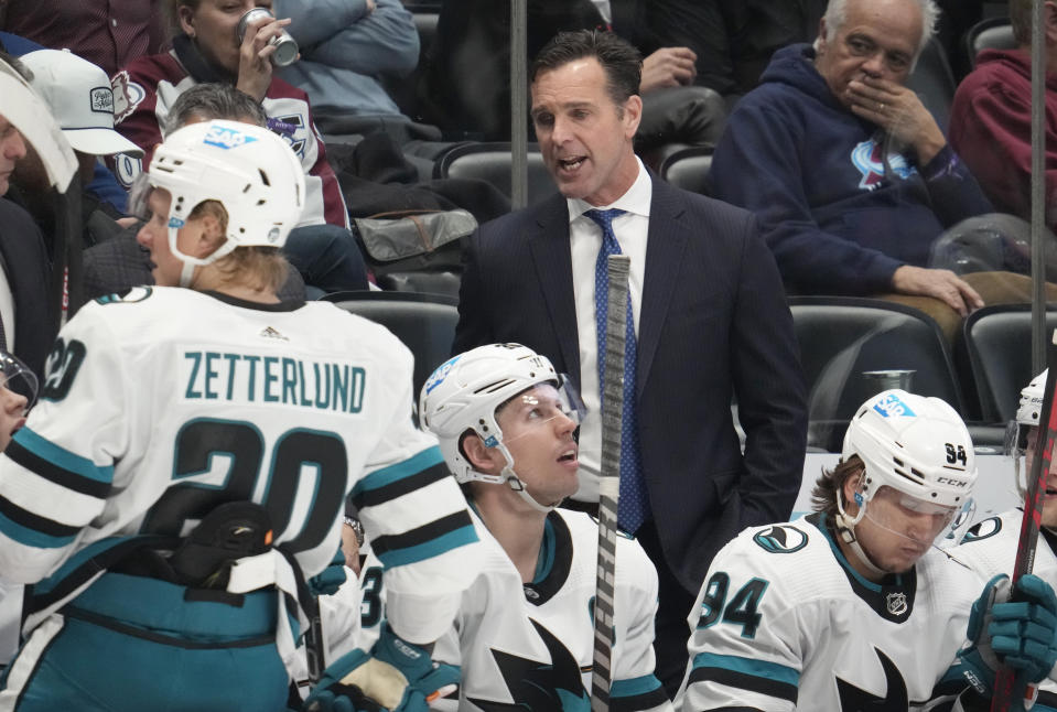San Jose Sharks head coach David Quinn, back, confers with players in the second period of an NHL hockey game against the Colorado Avalanche Tuesday, March 7, 2023, in Denver. (AP Photo/David Zalubowski)