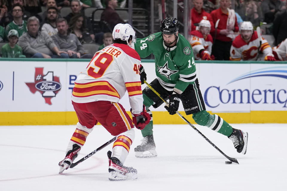 Dallas Stars left wing Jamie Benn takes a shot as Calgary Flames' Jakob Pelletier defends on the play in the first period of an NHL hockey game, Monday, March 6, 2023, in Dallas. (AP Photo/Tony Gutierrez)