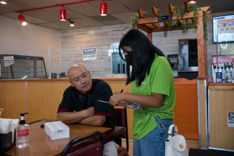 Jóvenes entregan pruebas de covid y folletos informativos a Chris Vang, propietario de Tiger Bite Bowls, un restaurante de fusión asiática en Fresno, California. Los jóvenes han sido capacitados como educadores de salud para promover las vacunas covid. Foto Heidi de Marco/KHN