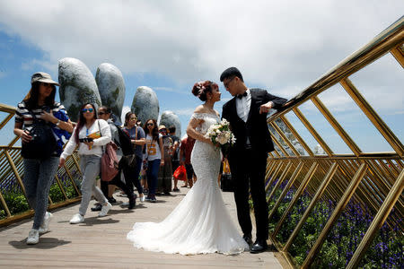 A couple pose near giant hands for their wedding photos on Gold Bridge on Ba Na hill near Danang city, Vietnam August 1, 2018. REUTERS/Kham