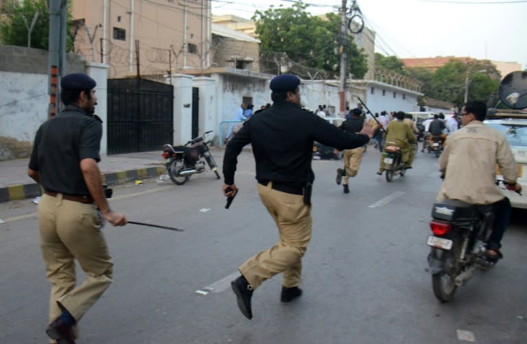 Pakistani policemen chase activists from the Muttahida Qaumi Movement (MQM) politicial party during a clash in Karachi on August 22, 2016