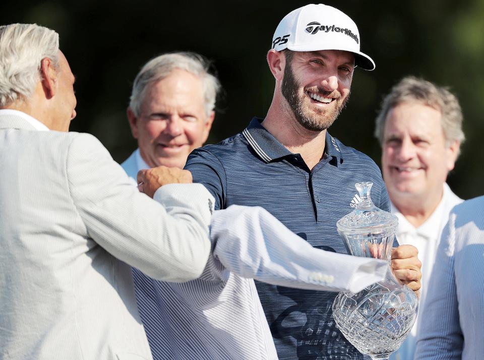 Dustin Johnson receives his seersucker jacket and trophy after holing out on the 18th hole to win the  FedEx St. Jude Classic Golf Tournament at Southwind in Memphis in June 2018.