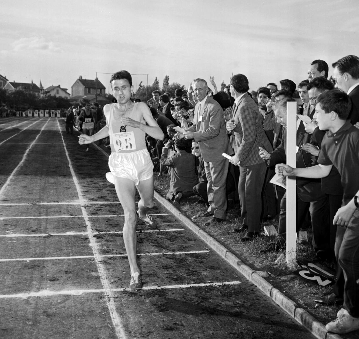 (FILES) France's Michel Jazy, cheered on by the crowd, crosses the finish line at a meeting in Melun on June 24, 1965, where he set two new world records, the 2-mile record in 8'22"6/10 and the 3000m record in 7'49". Former French athlete Michel Jazy died at 87 years-old announced the French Athletics Federation on February 1, 2024. (Photo by STAFF / AFP)