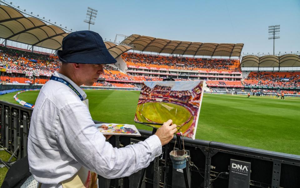 Andy Brown, a British artist, paints the cricket field during the play of first day of the first Test cricket match between India and England