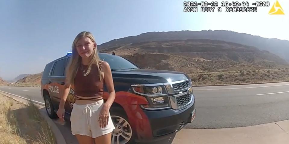 A still of police bodycam footage showing Gabby Petito outside a police car on August 12. She looks upset.