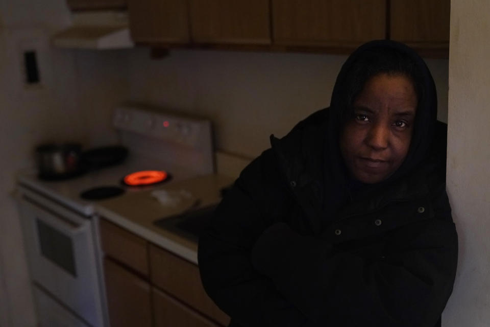 Genevieve Tyler stands for a portrait where she uses the stove's electric burner to heat the apartment she is living in Monday, Jan. 8, 2024, in Harvey, Ill. Tyler, who was recently laid off from her meat factory job, heard noises outside and ran for a second door in her apartment thinking it was a break-in. She then came upon crews boarding up her windows. "I feel sick," she said, adding that she was too scared to return home. "I'm still sad." (AP Photo/Charles Rex Arbogast)