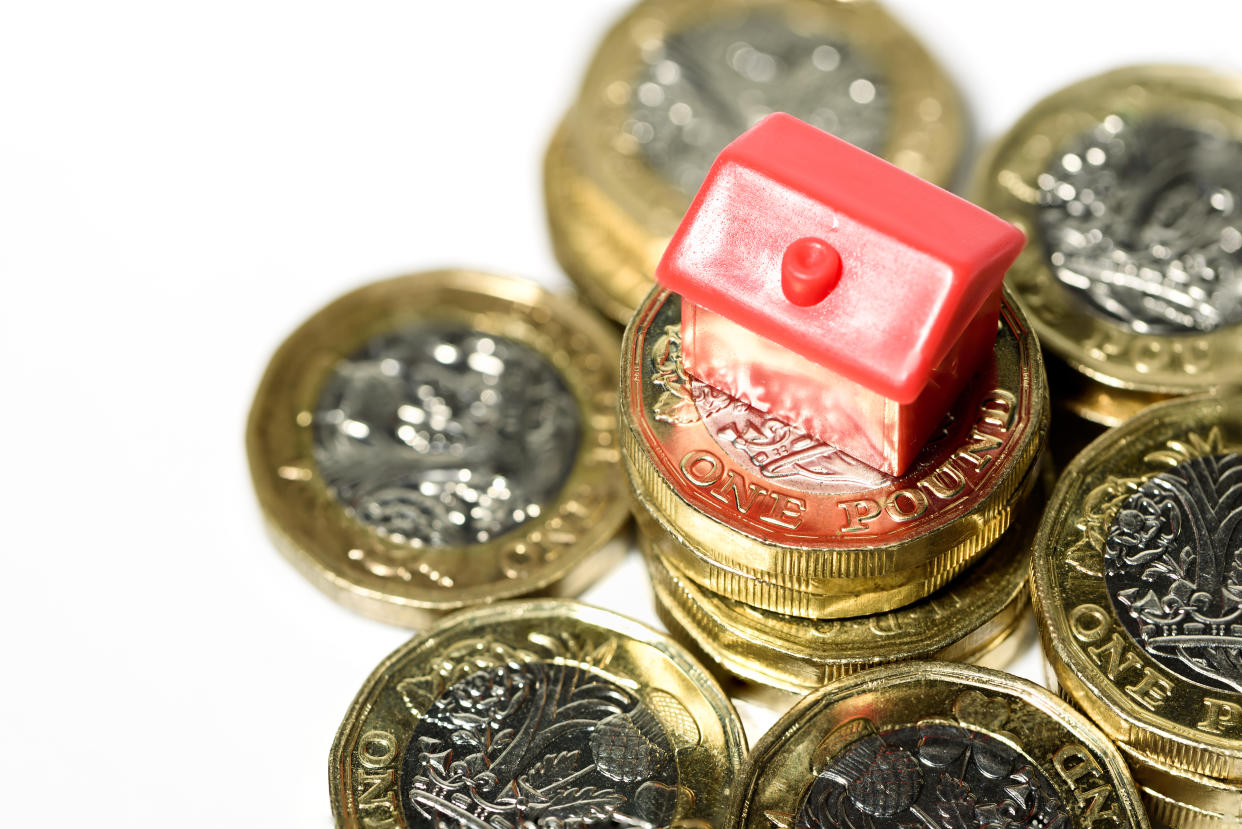 Macro close up of a Miniature house resting on new pound coins with a white background