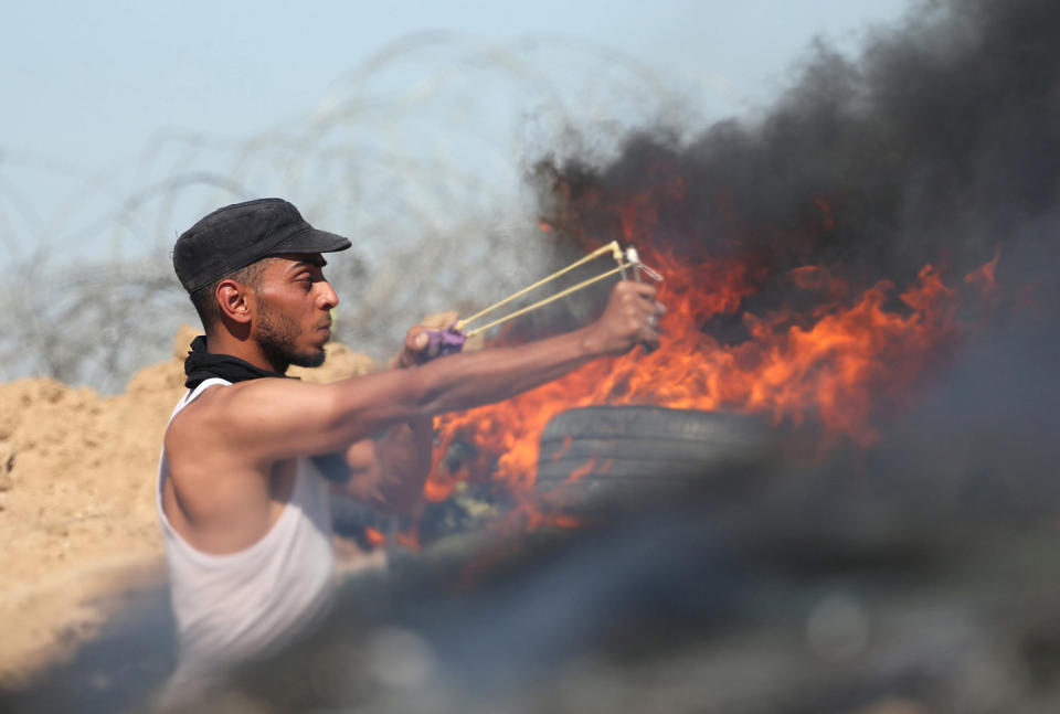 <p>A Palestinian protester uses a slingshot to hurl stones towards Israeli troops during clashes near the border between Israel and Central Gaza Strip, May 26, 2017. (Photo: Ibraheem Abu Mustafa/Reuters) </p>