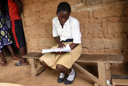 Mariatu Sesay, 15, checks her notes outside her house in a countryside village of Sierra Leone