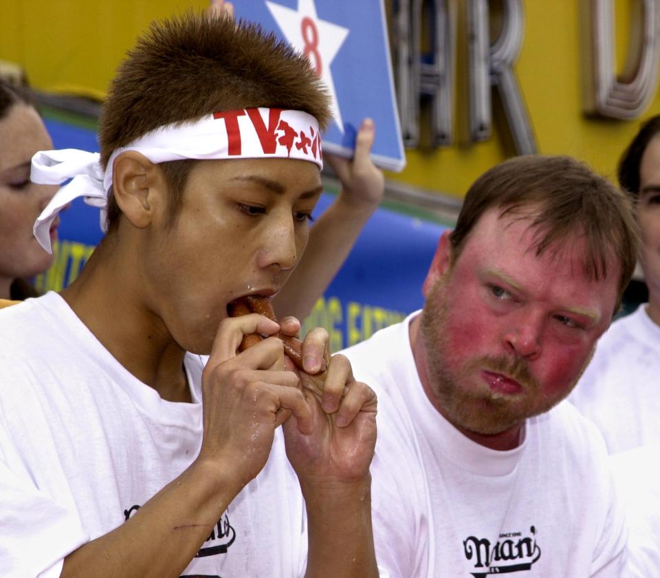 BROOKLYN, UNITED STATES:  Japan's Takeru Kobayashi (L), a 131 lbs. (59 kgs) 23-year-old from Nagano,  eats hot dogs during the Nathana's Hot Dog Eating Contest in Coney Island, Brooklyn, 04 July 2001.  Kobayashi  won the contest eating 50 hot dogs in 12 minutes, nearly doubled the old record. American Steve Addicks (R) looks on incredulously as Kobayahsi consumes two hot dogs at a time.   AFP PHOTO/Henny Ray ABRAMS (Photo credit should read HENNY RAY ABRAMS/AFP/Getty Images)