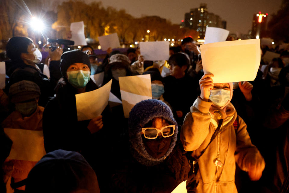 People gather for a vigil and hold white sheets of paper in protest of coronavirus disease (COVID-19) restrictions, as they commemorate the victims of a fire in Urumqi, as outbreaks of the coronavirus disease continue in Beijing, China, November 27, 2022. REUTERS/Thomas Peter