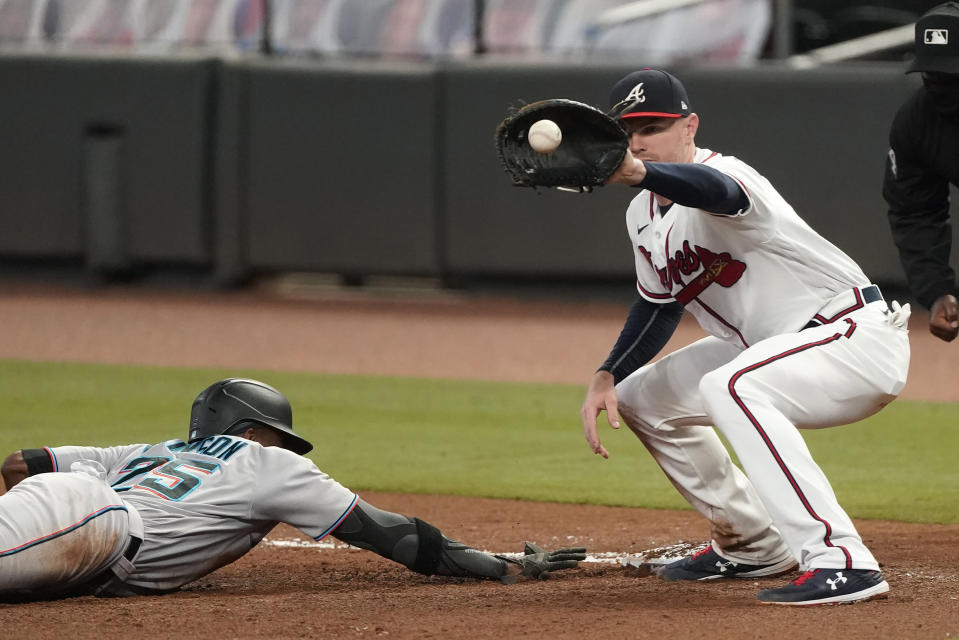 Miami Marlins' Lewis Brinson (25) dives back to first base ahead of the throw to Atlanta Braves first baseman Freddie Freeman (5) in the fourth inning of a baseball game Wednesday, Sept. 23, 2020, in Atlanta. (AP Photo/John Bazemore)