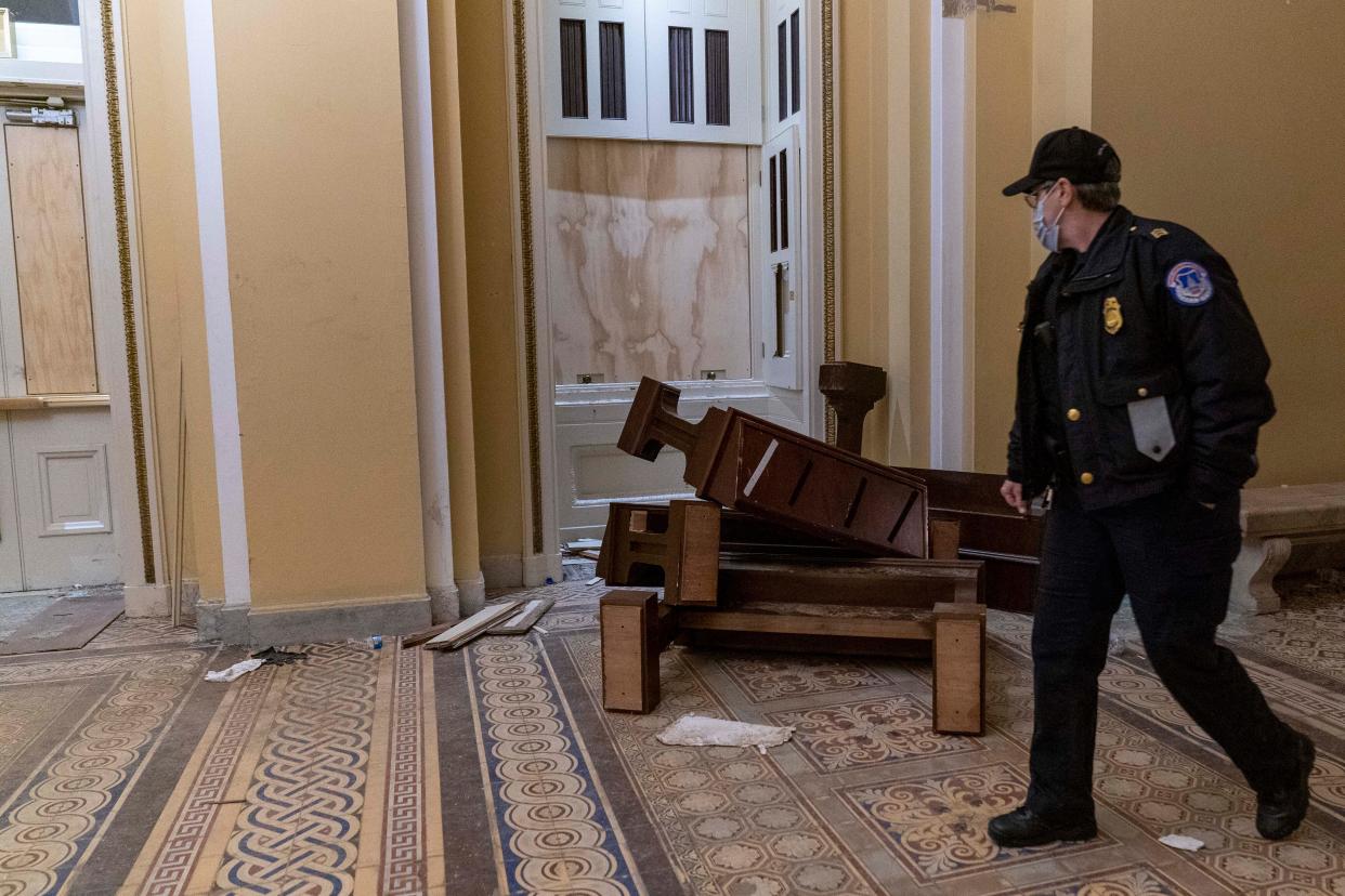 A U.S. Capitol Police officer walks past damage in the early morning hours of Thursday, Jan. 7, 2021, after protesters stormed the Capitol in Washington on Wednesday.