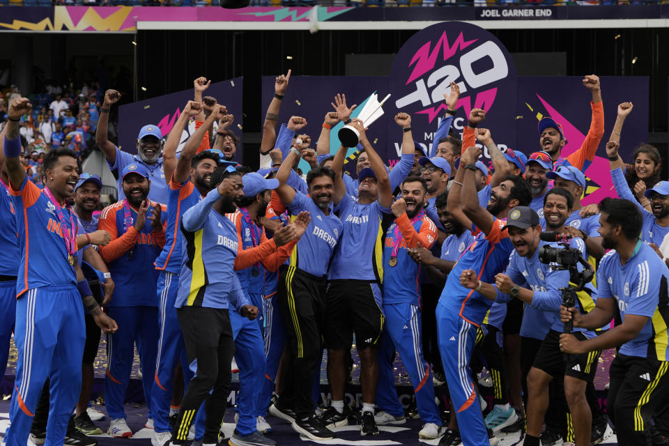 India's head coach Rahul Dravid, center, and players celebrate with the winners trophy after defeating South Africa in the ICC Men's T20 World Cup final cricket match at Kensington Oval in Bridgetown, Barbados, Saturday, June 29, 2024. (AP Photo/Ricardo Mazalan)