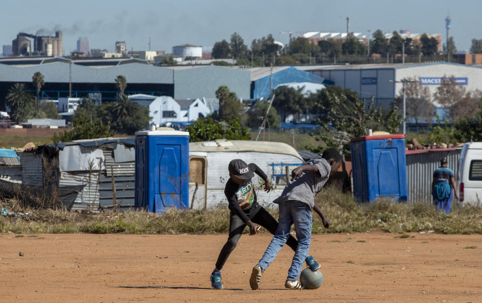 Young boys play soccer on a dusty field at Ramaphosa informal settlement, east of Johannesburg, South Africa, Tuesday, April 28, 2020. South Africa will begin a phased easing of its strict lockdown measures on May 1, although confirmed cases of coronavirus continue to increase. (AP Photo/Themba Hadebe)