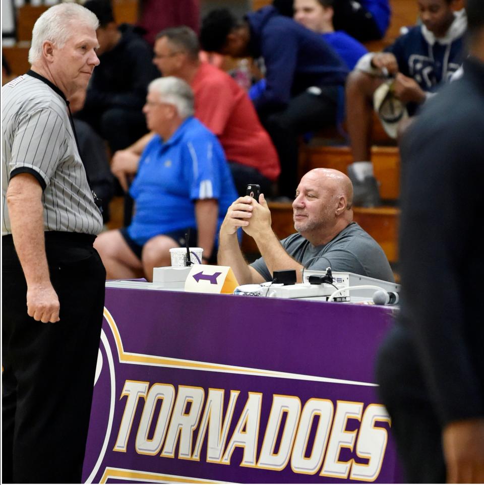 Dennis Maffezzoli checks his cell phone during a break in a Booker High basketball game. Maffezzoli is retiring after 48 years in sports journalism.