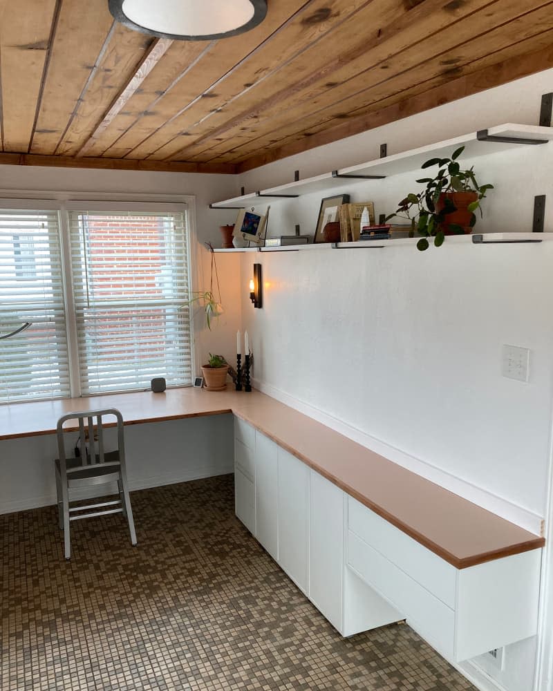 L-shaped work space in room with upper shelving and wood ceiling.