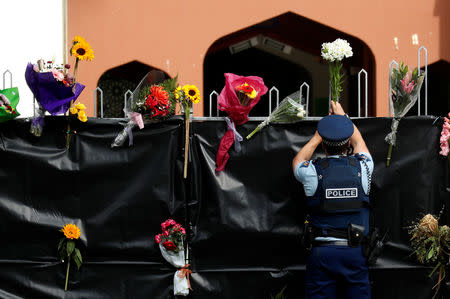 A police officer places flowers at the entrance of Masjid Al Noor mosque in Christchurch, New Zealand, March 17, 2019. REUTERS/Jorge Silva