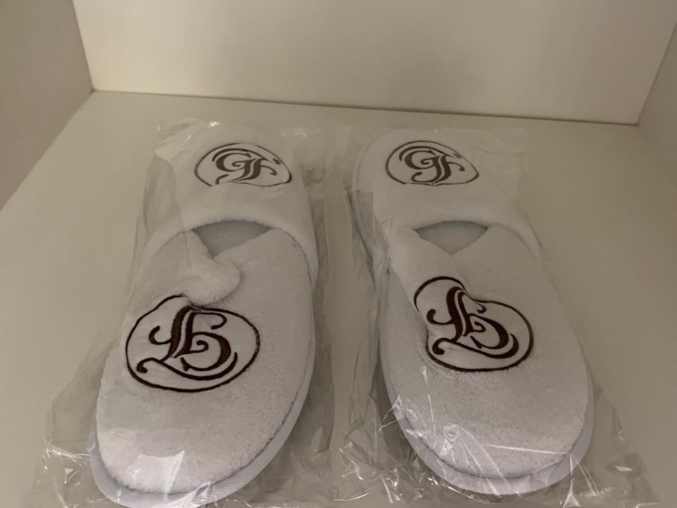 two pairs of white grand floridian slippers in plastic wrappings in a closet inside a room at the grand floridian resort