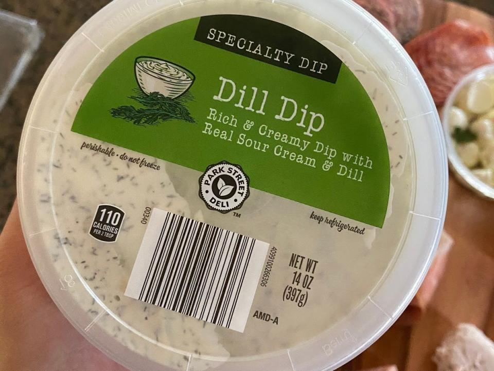 hand holding container of aldi dill dip