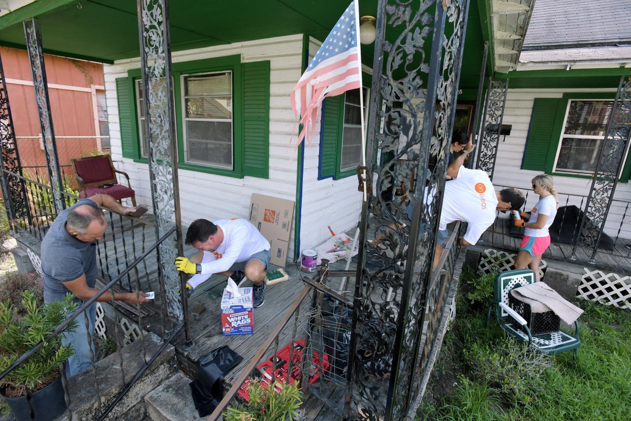 Volunteers scrape and repaint the metalwork on the porch of a home on Van Buren Street on Jacksonville's Eastside as part of the United Way of Northeast Florida's Freedom Weekend in 2021.