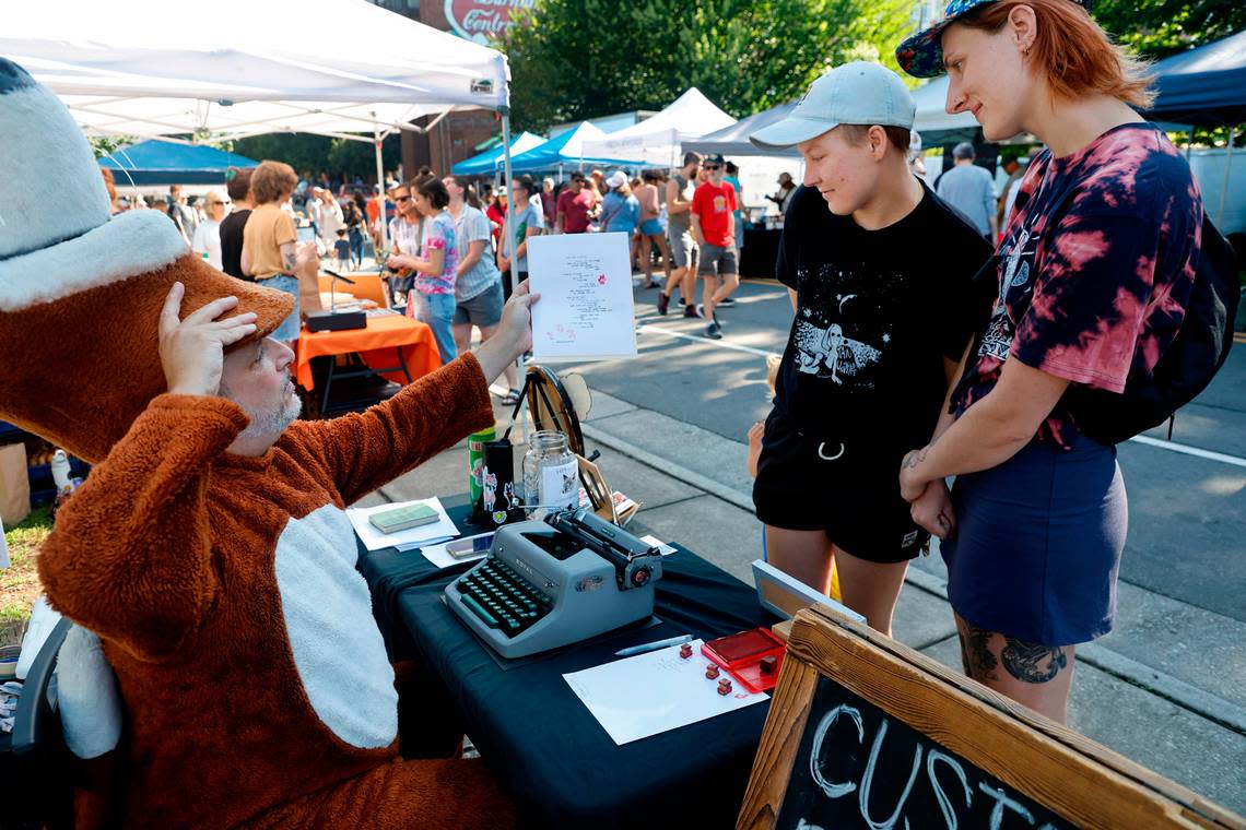 Chris Vitiello, otherwise known as the Poetry Fox, reads the poem he wrote for Bec Alderson, left, and her partner Sarah Jenkins while at the Hunt Street Art and Food Truck Market in Durham, N.C., Saturday morning, June 24, 2023.