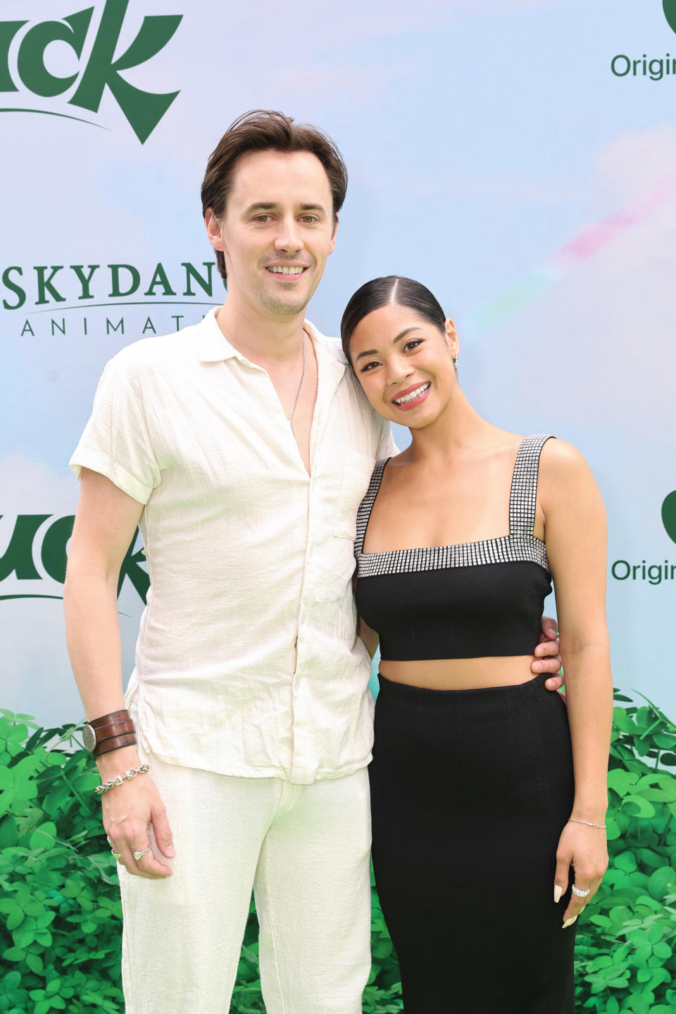 Two people posing.  One is wearing white casual clothes and the other is wearing a square neck black top.