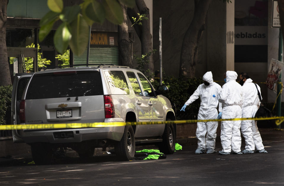 Forensic investigators work in the area where an abandoned vehicle that is believed to have been used by gunmen in an attack against the chief of police is sealed off with yellow tape, in Mexico City, Friday, June 26, 2020. Heavily armed gunmen attacked and wounded police chief Omar Garcia Harfuch in a brazen operation that left an unspecified number of dead, Mayor Claudia Sheinbaum said Friday. (AP Photo/Marco Ugarte)