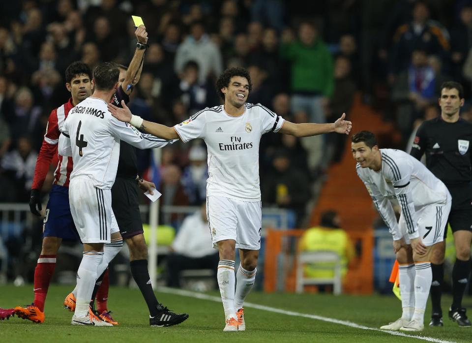 Real's Pepe, center, and Cristiano Ronaldo, right, laugh as Pepe gets a yellow card during the semifinal, 1st leg, Copa del Rey soccer derby match between Real Madrid and Atletico Madrid at the Santiago Bernabeu Stadium in Madrid, Wednesday Feb. 5, 2014. (AP Photo/Paul White)