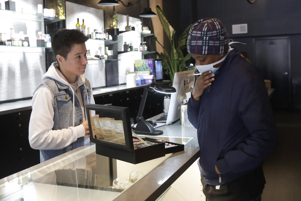 Customer Antoine Conners, right, wears a mask while being helped by budtender Chris Gomez at The Mission Cannabis Club dispensary in San Francisco, Thursday, March 19, 2020. (AP Photo/Jeff Chiu)