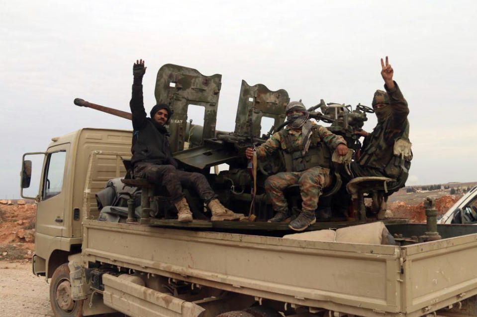 In this photo released Sunday, Feb. 16, 2020 by the Syrian official news agency SANA, Syrian army soldiers flash the victory sign as they patrol the village of Tallet Shweihna, in Aleppo province, Syria. On Monday Syria's military announced its troops have regained control of territories in northwestern Syria "in record time," vowing to continue to chase armed groups "wherever they are." (SANA via AP)