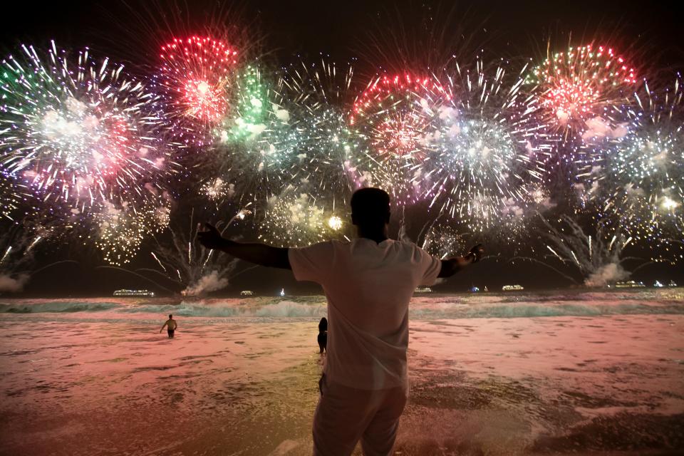 A man celebrates the start of the New Year as fireworks illuminate Copacabana Beach in Rio de Janeiro, Brazil, early Monday, 1 January 2024 (AP)