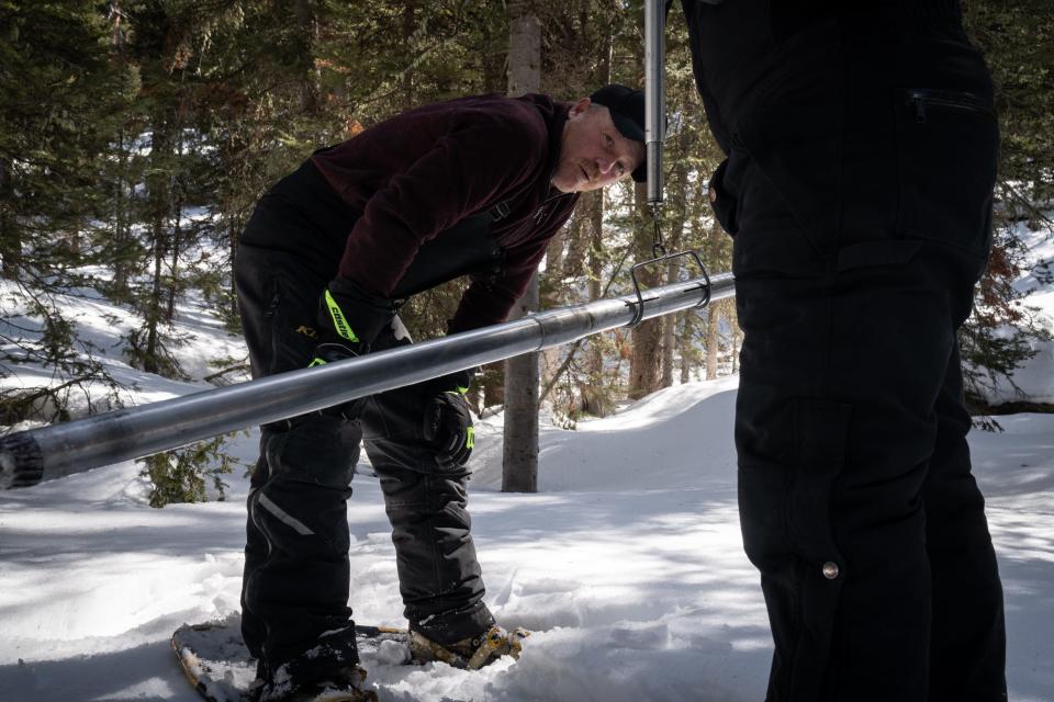 Wade Payne (left) takes the weight of a core snow sample, while his brother Kevin Payne holds the scale at Horse Creek, west of Pinedale, Wyoming, on March 25, 2022. The snow water equivalent, or the amount of water contained in snowpack, is then calculated for the site.