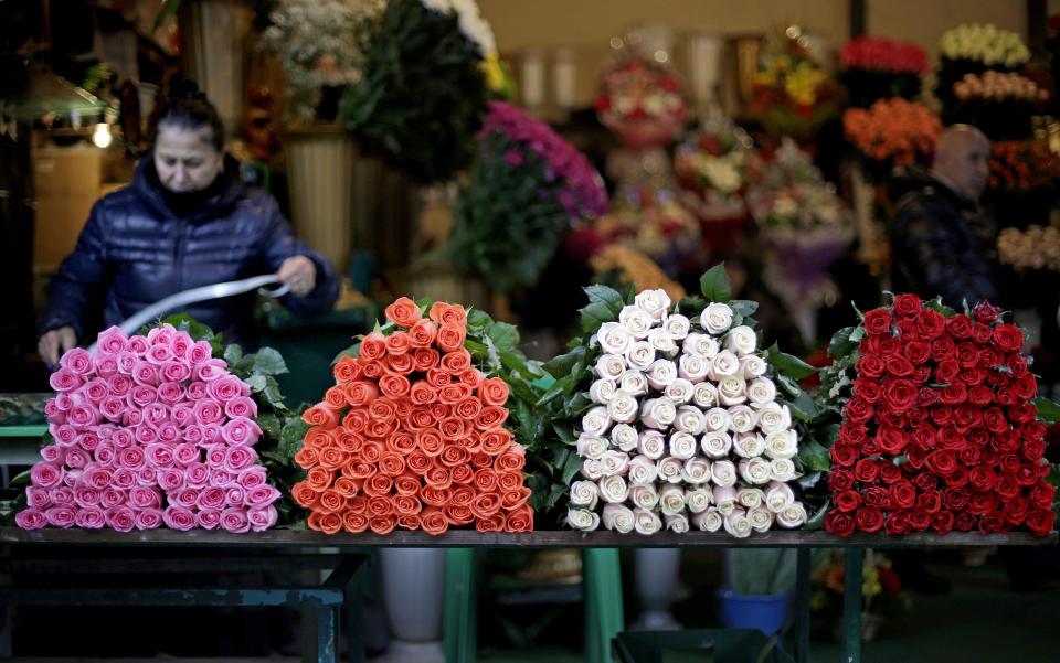 Roses sit on a table at a flower shop in a marketplace as a woman prepares a bouquet, Wednesday, Jan. 29, 2014, in Sochi, Russia, home of the upcoming 2014 Winter Olympics. (AP Photo/David Goldman)