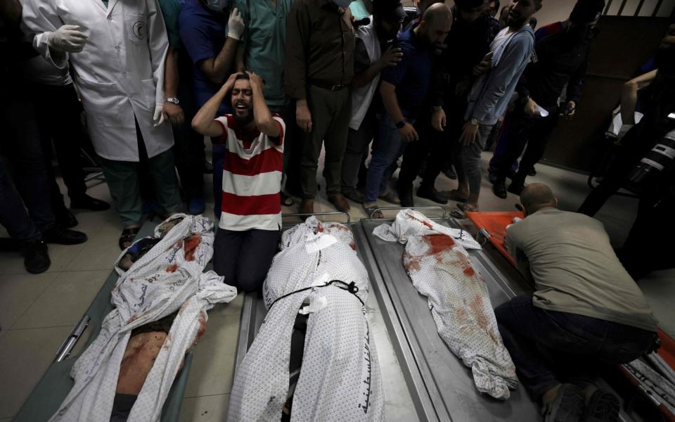 Relatives of the Abu Hatab family mourn over the bodies of their family members in Al-Shifa Hospital, after an Israeli air strike struck their house in Gaza's al-Shati Refugee Camp without warning on Saturday night - AFP