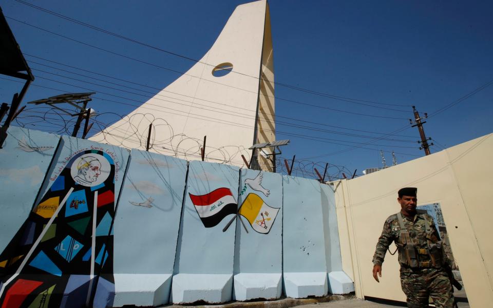 An Iraqi soldier stands guard by a concrete wall placed by security forces to surround the Our Lady of Salvation Church in Baghdad - AP