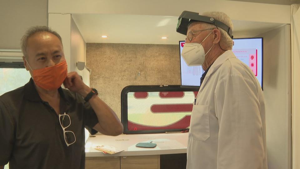 Andy Jun (left) getting checked by Dr. Mike Connolly (right) at the mole mobile cancer screening unit on wheels (Lamia Abozaid/CBC - image credit)