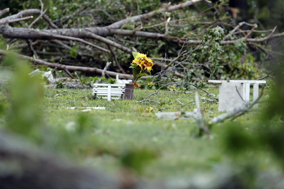 Flowers at a grave site sits amongst debris at Highland Memorial Park Cemetery, Friday, Aug. 18, 2023, in Johnston, R.I., after severe weather swept through the area. (AP Photo/Michael Dwyer)