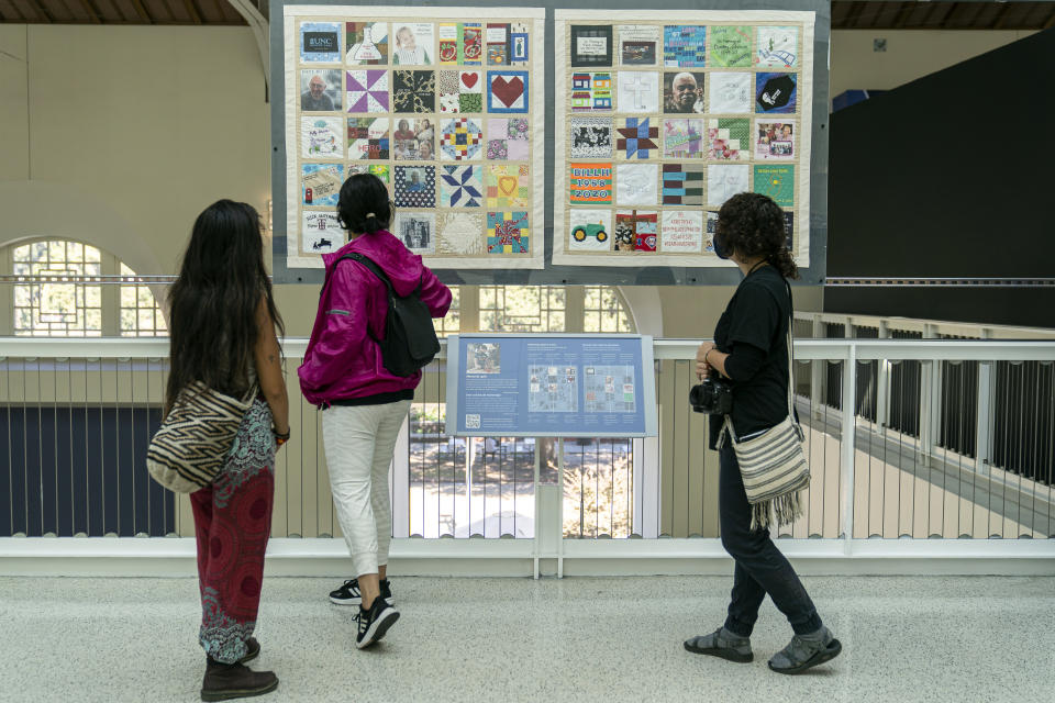 High school students pause in front of a few panels of Madeleine Fugate's COVID Memorial Quilt to honor those who died of COVID-19, displayed at the California Science Center in Los Angeles on Tuesday, Oct. 19, 2021. Fugate's memorial quilt started out in May 2020 as a seventh grade class project. Inspired by the AIDS Memorial Quilt, which her mother worked on in the 1980s, the then-13-year-old encouraged families in her native Los Angeles to send her fabric squares representing their lost loved ones that she'd stitch together. (AP Photo/Damian Dovarganes)