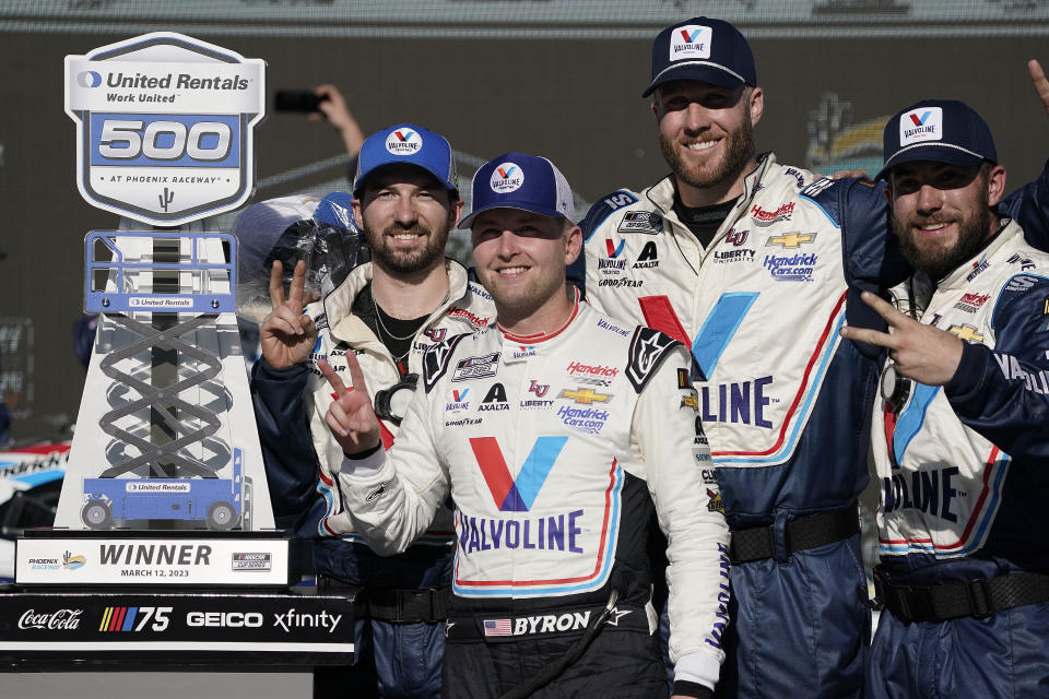William Byron, front, and team members pose with the trophy after winning a NASCAR Cup Series auto race at Phoenix Raceway, Sunday, March 12, 2023, in Avondale, Ariz. (AP Photo/Darryl Webb)