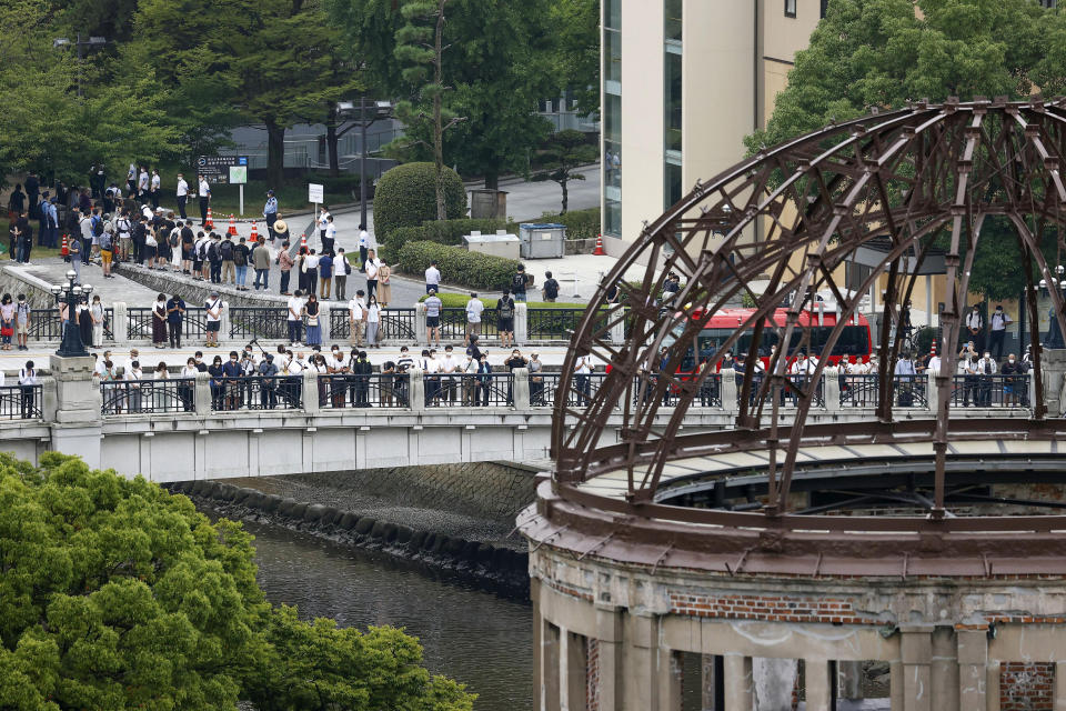 Visitors observe a minute of silence for the victims of the atomic bombing, at 8:15am, the time atomic bomb exploded over the city, at the Hiroshima Peace Memorial Park during the ceremony to mark the 77th anniversary of the bombing, in Hiroshima, western Japan Saturday, Aug. 6, 2022. The Atomic Bomb Dome is seen at front right.(Kyodo News via AP)